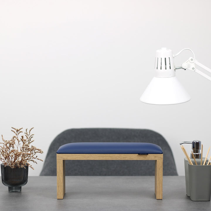 SPENVI Classic manicure arm rest with blue leather cushion and oak-finish legs on modern salon desk under white lamp. #color_blue