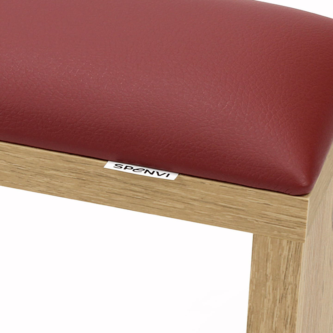 Close-up of SPENVI Classic manicure arm rest with red leather cushion and oak-finish wooden base. #color_bordo