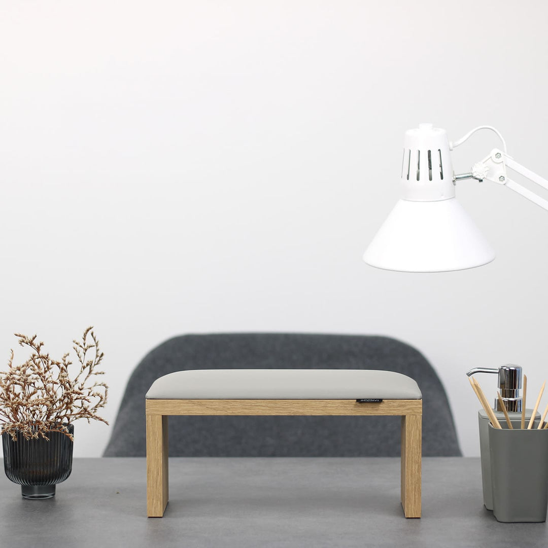 SPENVI Classic manicure arm rest with light gray leather cushion and oak-finish legs on modern salon desk under white lamp. #color_cloud
