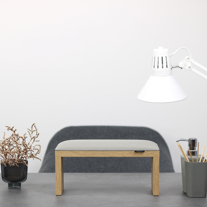 SPENVI Classic manicure arm rest with light gray leather cushion and oak-finish legs on modern salon desk under white lamp. #color_cloud