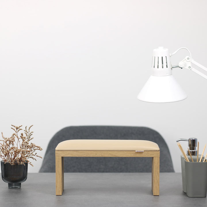 SPENVI Classic manicure arm rest with beige leather cushion and oak-finish legs on modern salon desk under white lamp. #color_coffee-milk