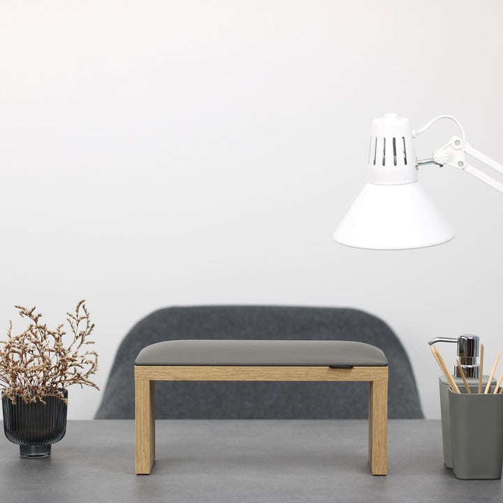 SPENVI Classic manicure arm rest with gray leather cushion and oak-finish legs on modern salon desk under white lamp. #color_gray