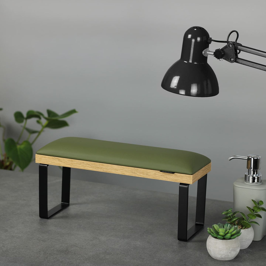 SPENVI Loft manicure arm rest with khaki leather cushion, oak-finish base, and black metal legs on modern salon desk with lamp and plants. #color_khaki