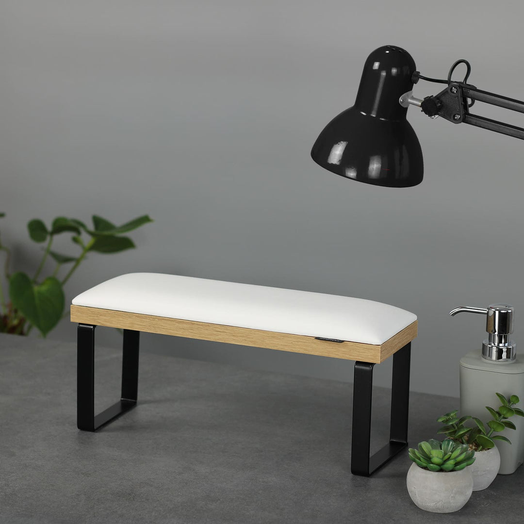 SPENVI Loft manicure arm rest with white leather cushion, oak-finish base, and black metal legs on modern salon desk with lamp and plants. #color_white