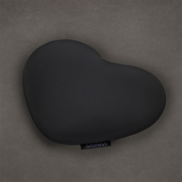 Black heart-shaped SPENVI nail tech elbow cushion made of soft leather on a textured grey background. #color_black