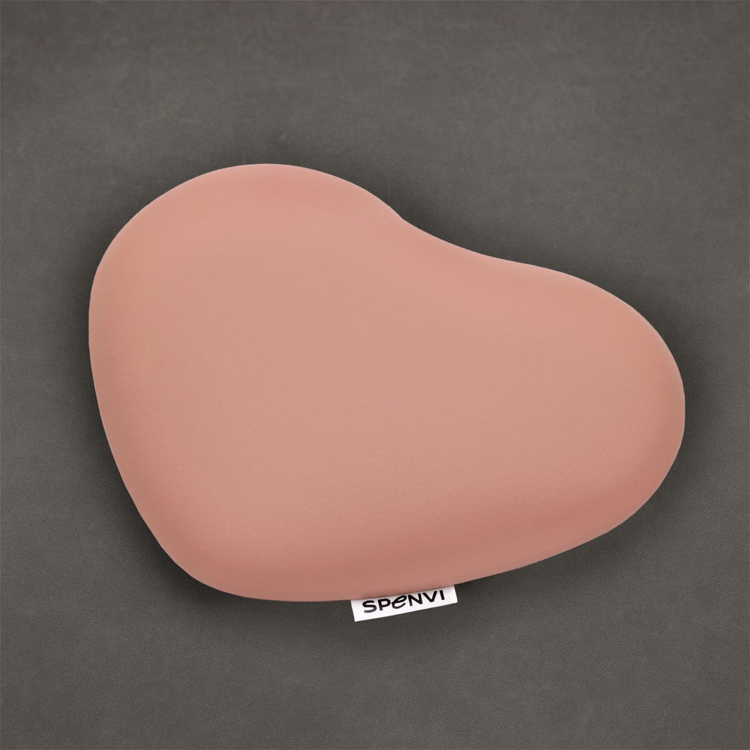Light pink heart-shaped SPENVI nail tech elbow cushion made of soft leather on a textured grey background. #color_light-pink