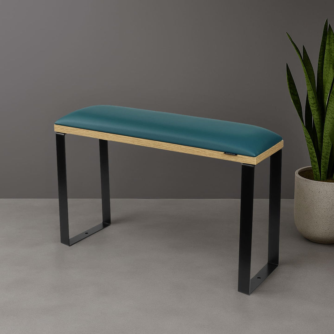 SPENVI Loft pedicure footrest with dark green leather cushion, oak-finish base, and black metal legs styled in modern salon interior with plant. #color_dark-green