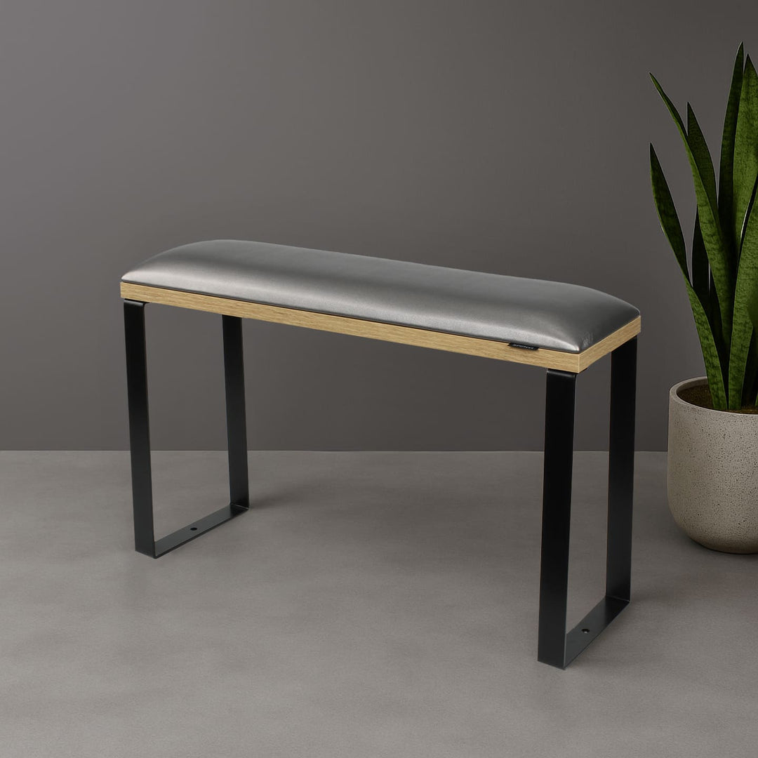 SPENVI Loft pedicure footrest with graphite leather cushion, oak-finish base, and black metal legs styled in modern salon interior with plant. #color_graphite